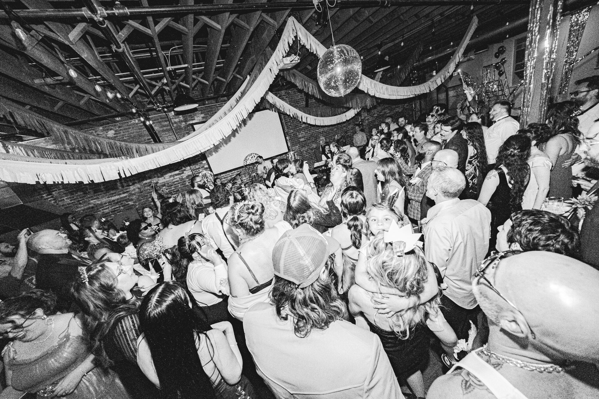 A packed dance floor under a disco ball at a wedding reception